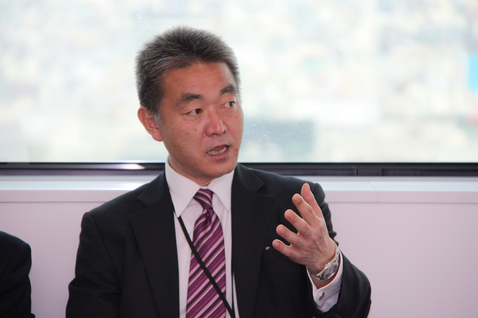 スーツ姿の男性が手振りを交えて話している写真