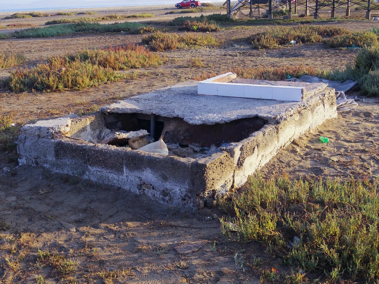 荒れた土地に壊れたコンクリートの基礎が残されている写真