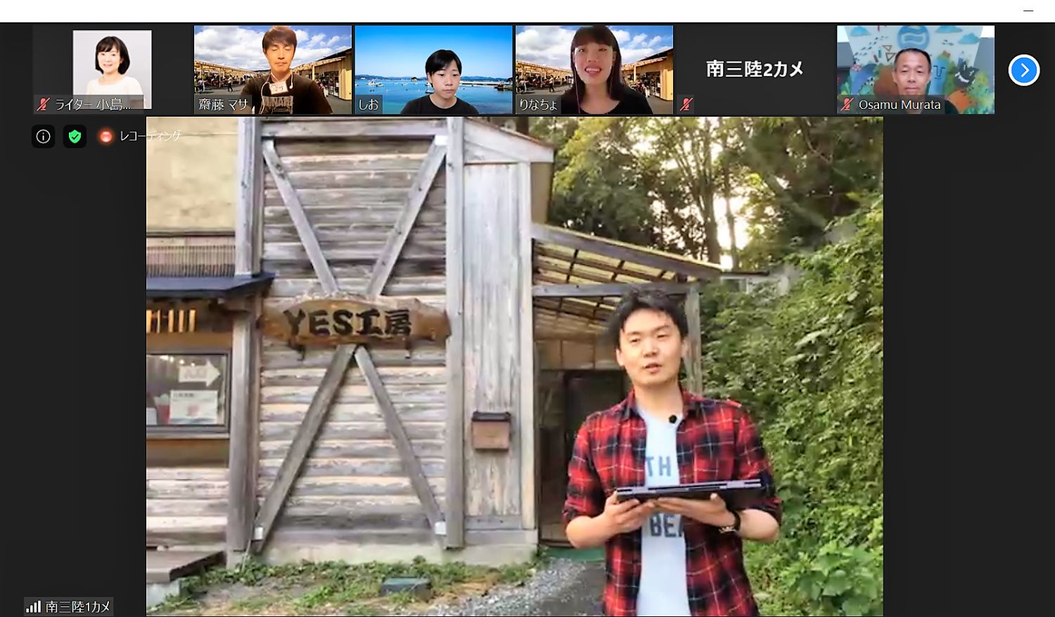 オンラインツアーの画面で、大森丈広さんが屋外の木造建物の前に立っている様子を映した写真