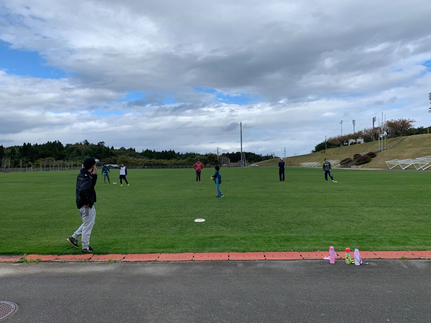 芝生の上でフリスビーをしている人々が広がってフリスビーを楽しんでいる写真