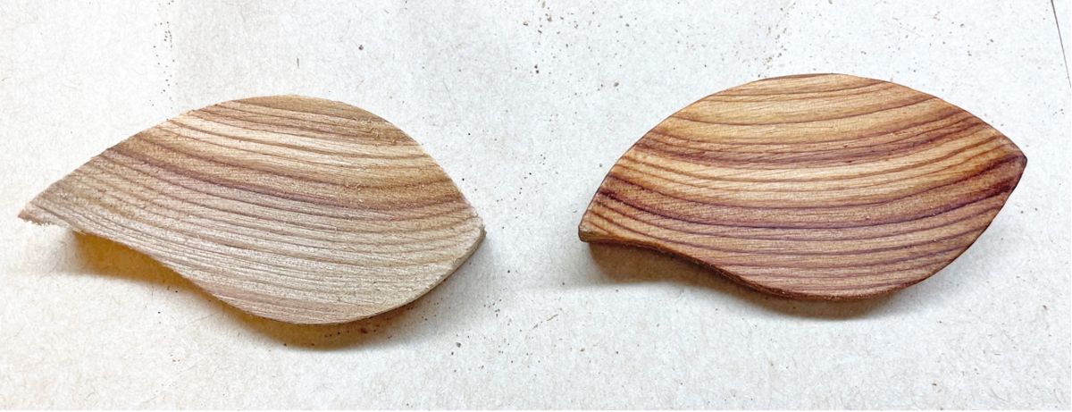左側に表面が白っぽく乾燥して見える木の葉型パーツ、右側にオイルを塗って艶が出た同じ形の木のパーツを並べた木材のオイル塗布前後比較の写真