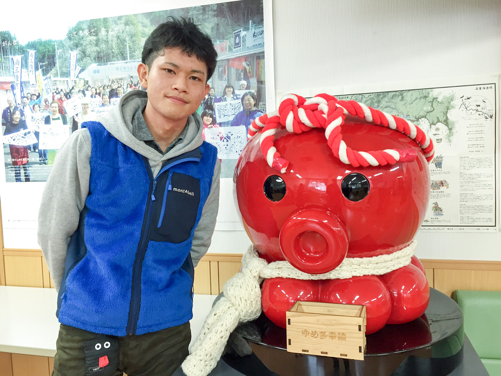 手前に賽銭箱が置かれた、紅白のねじり鉢巻きをした赤いタコのキャラクター「オクトパス君」の大きな像の横に立った星野さんの写真