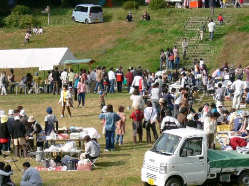 ひころの里ふれあい広場の広々とした会場で、白いテントが張られ、多くの来場者で賑わっているイベントの様子の写真