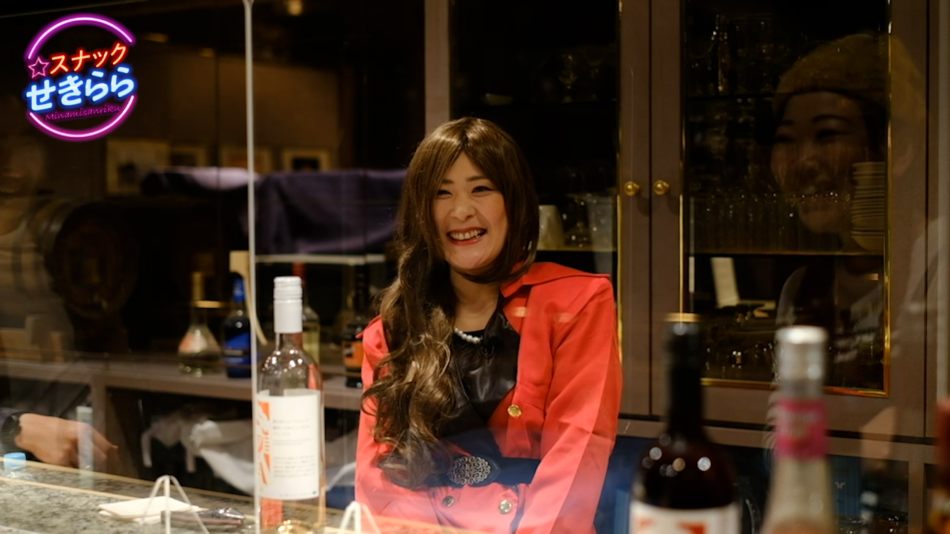 赤い服を着た女性がカウンターの向こう側で笑顔で座っている写真