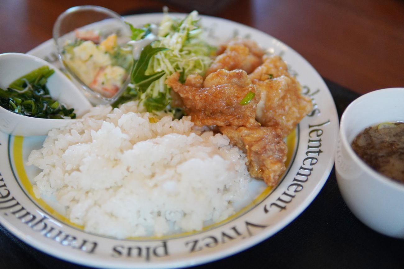 白いお皿に、ご飯とからあげ、サラダ、小鉢、スープがセットになった定食プレートの写真