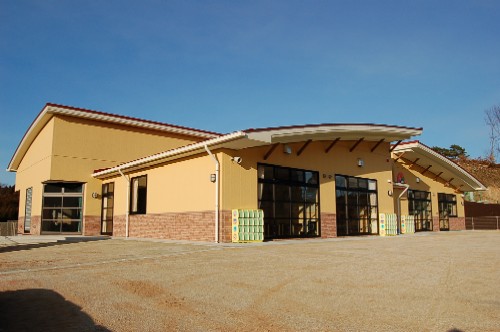 緩やかなカーブを描いた屋根と黄土色の外壁、茶色のレンガ風のタイルが特徴的な名足保育園新園舎の外観写真