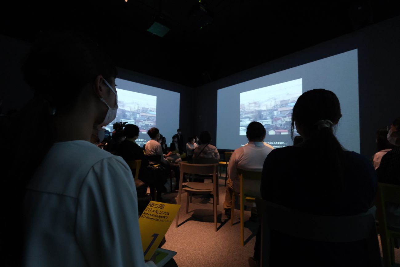 来館者がスクリーンに映し出された震災当時の映像や語りを視聴している写真