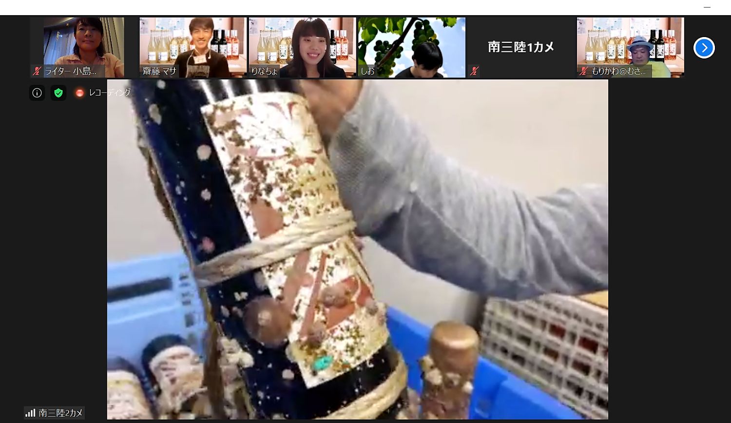 海中で熟成して引き上げたワインを画面越しにオンラインツアーの参加者たちに見せている写真