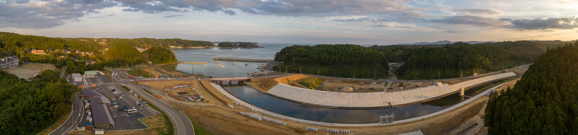 港と川に囲まれた町と海岸線を一望する高台からの夕方のパノラマ風景の写真