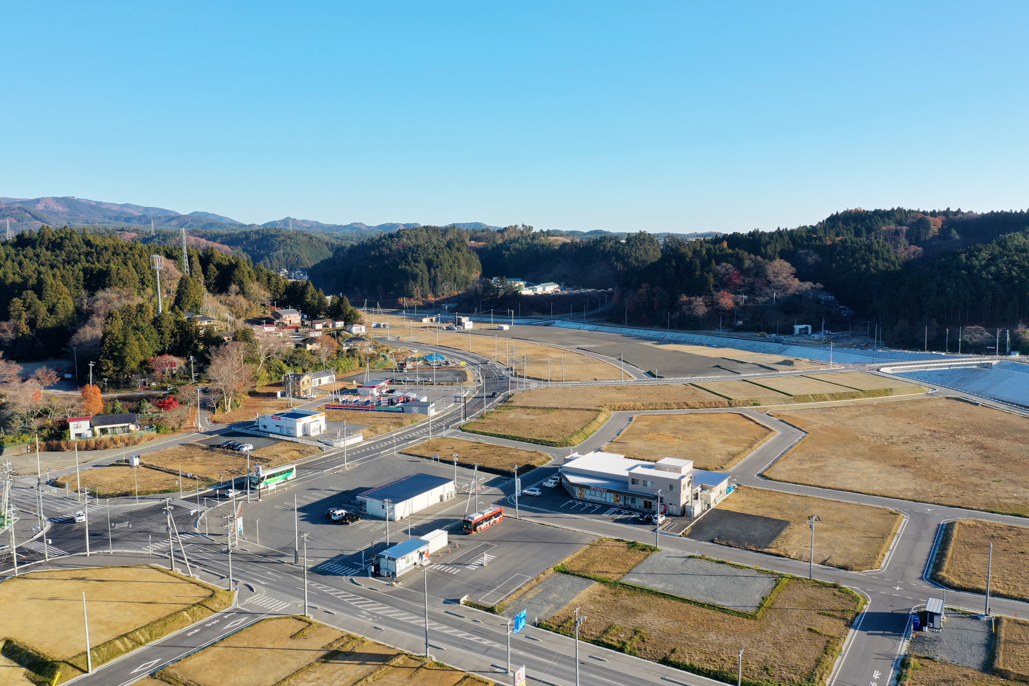 広々とした田園地帯の中に複数の建物と道路が点在しており、自然の中に人の暮らしが溶け込んでいる様子が見える写真