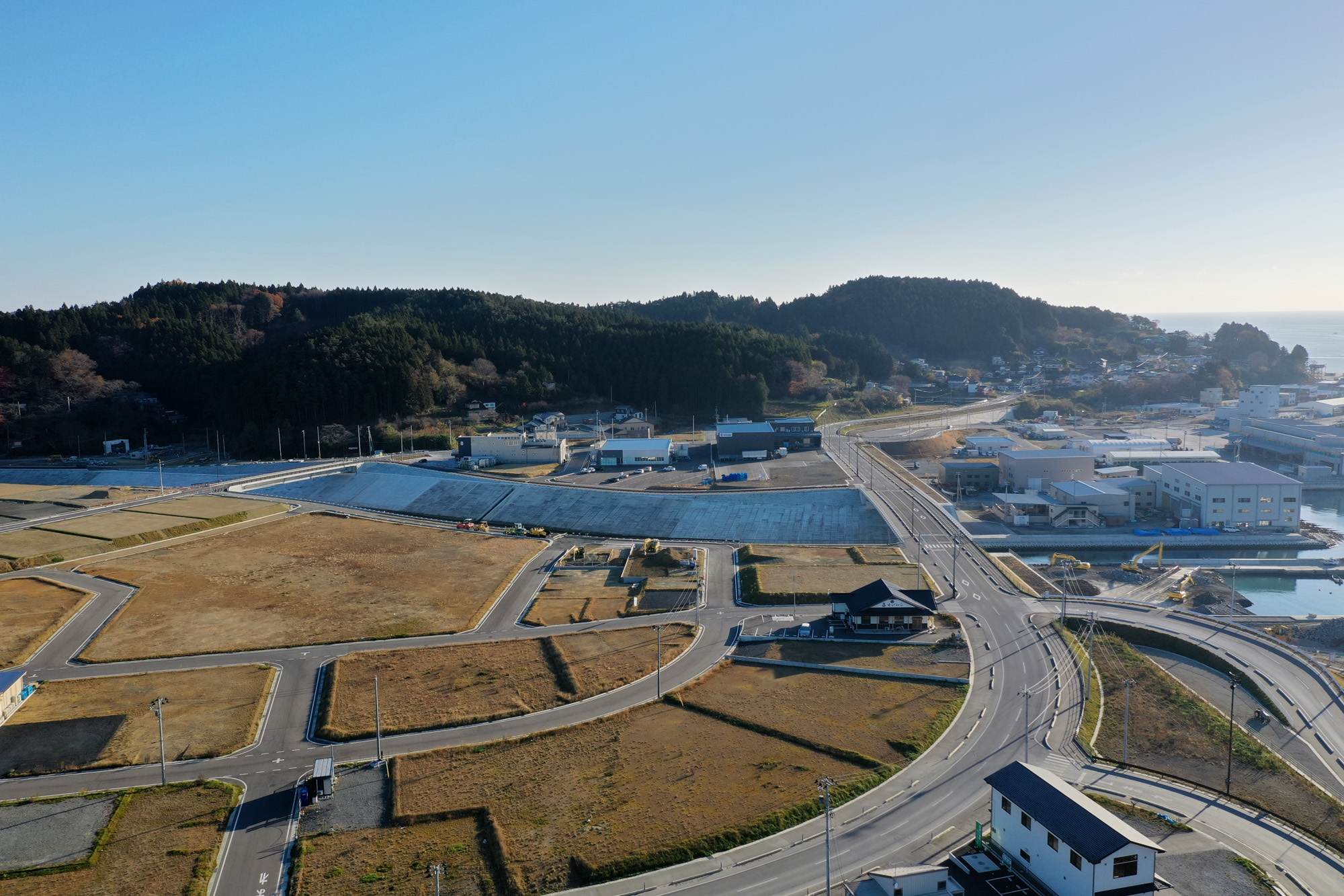 山々に囲まれた広い空き地の中を複数の道路が交差しており、自然の中に整備された交通インフラが広がっている様子が見える写真
