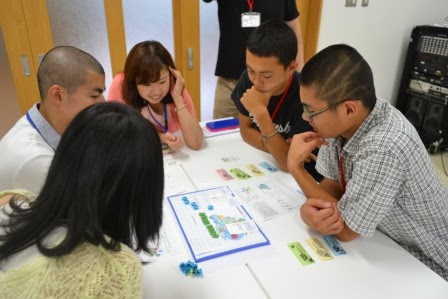 テーブルを囲んだ若者たちが、資源循環型地域産業育成ゲームのワークに集中して取り組んでいる写真