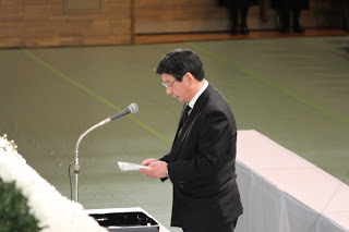 佐藤町長が祭壇に向かって置かれたマイクの前に立ち、式辞を述べている様子を写した写真