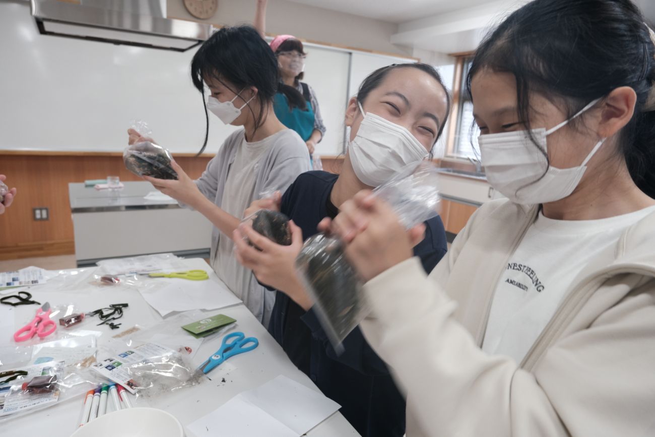 子どもたちが袋に入った海藻などを楽しそうに振っている様子の写真