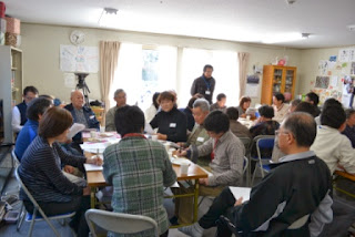 参加者たちが資料を手にまちづくりのアイデアを出し合っている活発な話し合いの様子の写真