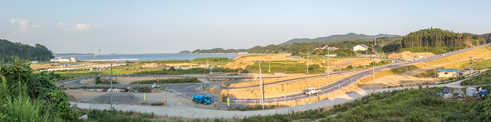 海沿いの広大な土地で道路やインフラの整備が進み、復興途中の町の姿を捉えたパノラマ写真
