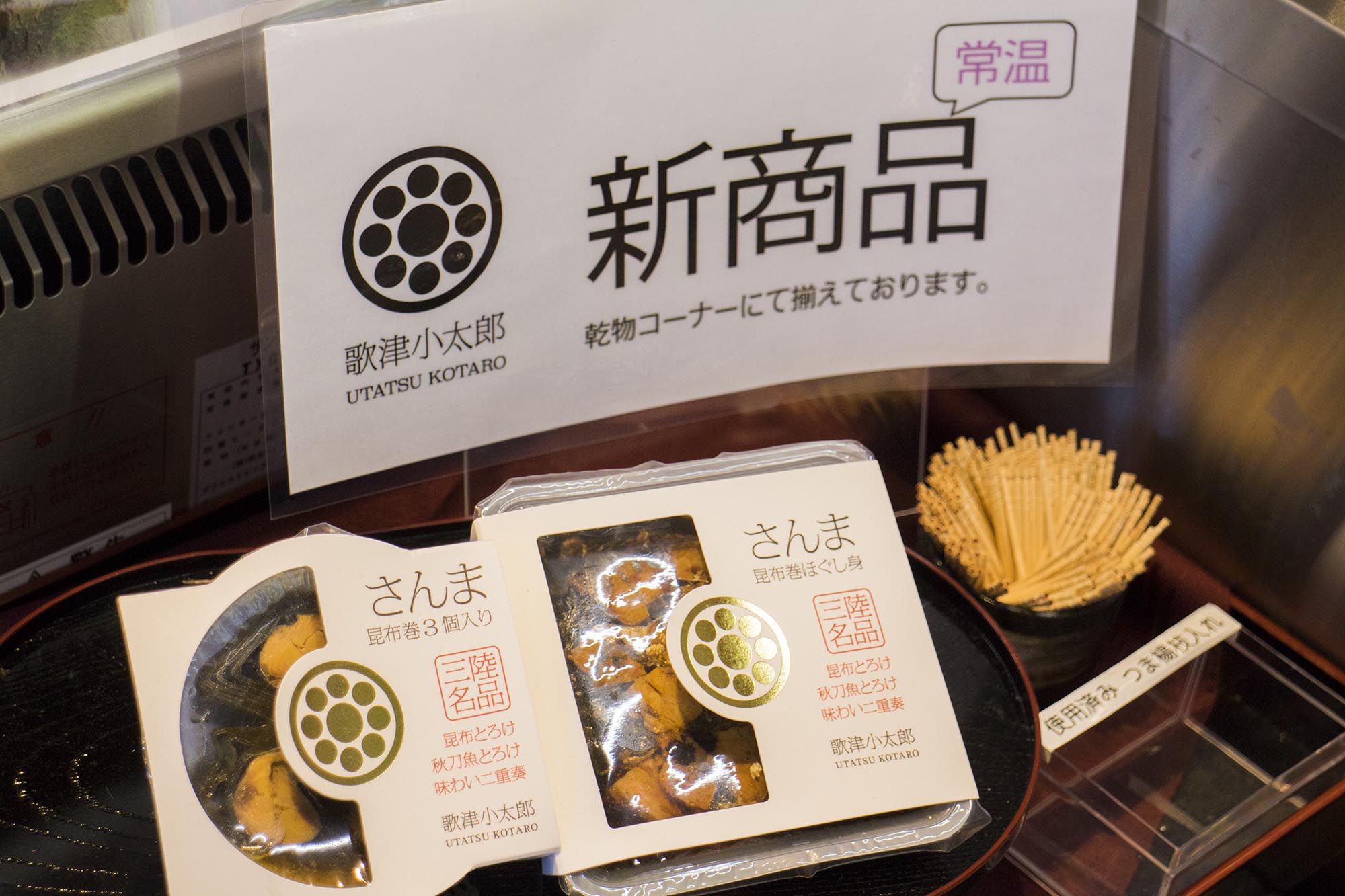 「新商品」と書かれたポップの前に、「さんま昆布巻き」などのパッケージ商品が陳列されている写真