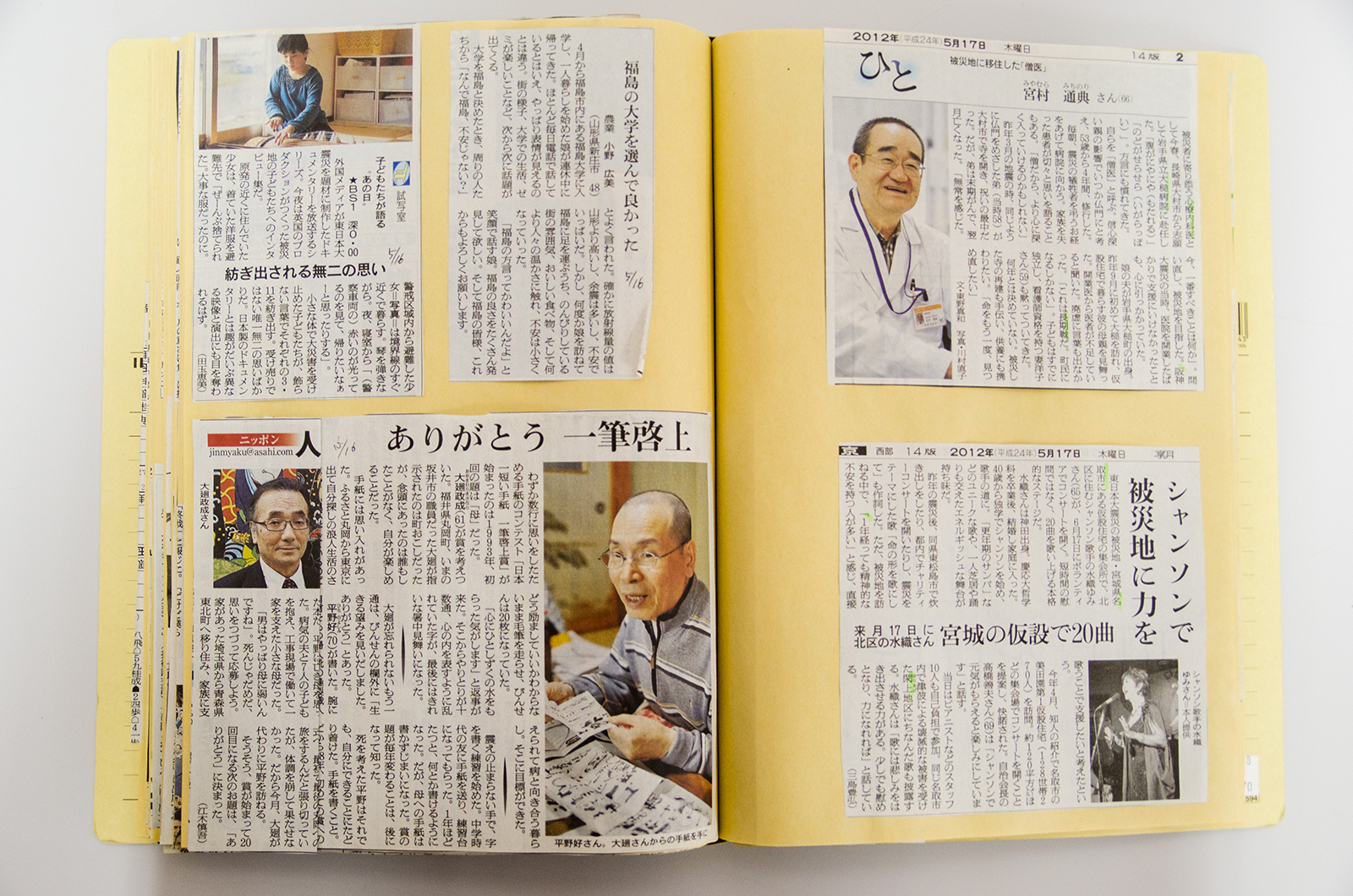 人物などが掲載された5枚の新聞の切り抜きが貼られたスクラップブックの見開きページの写真