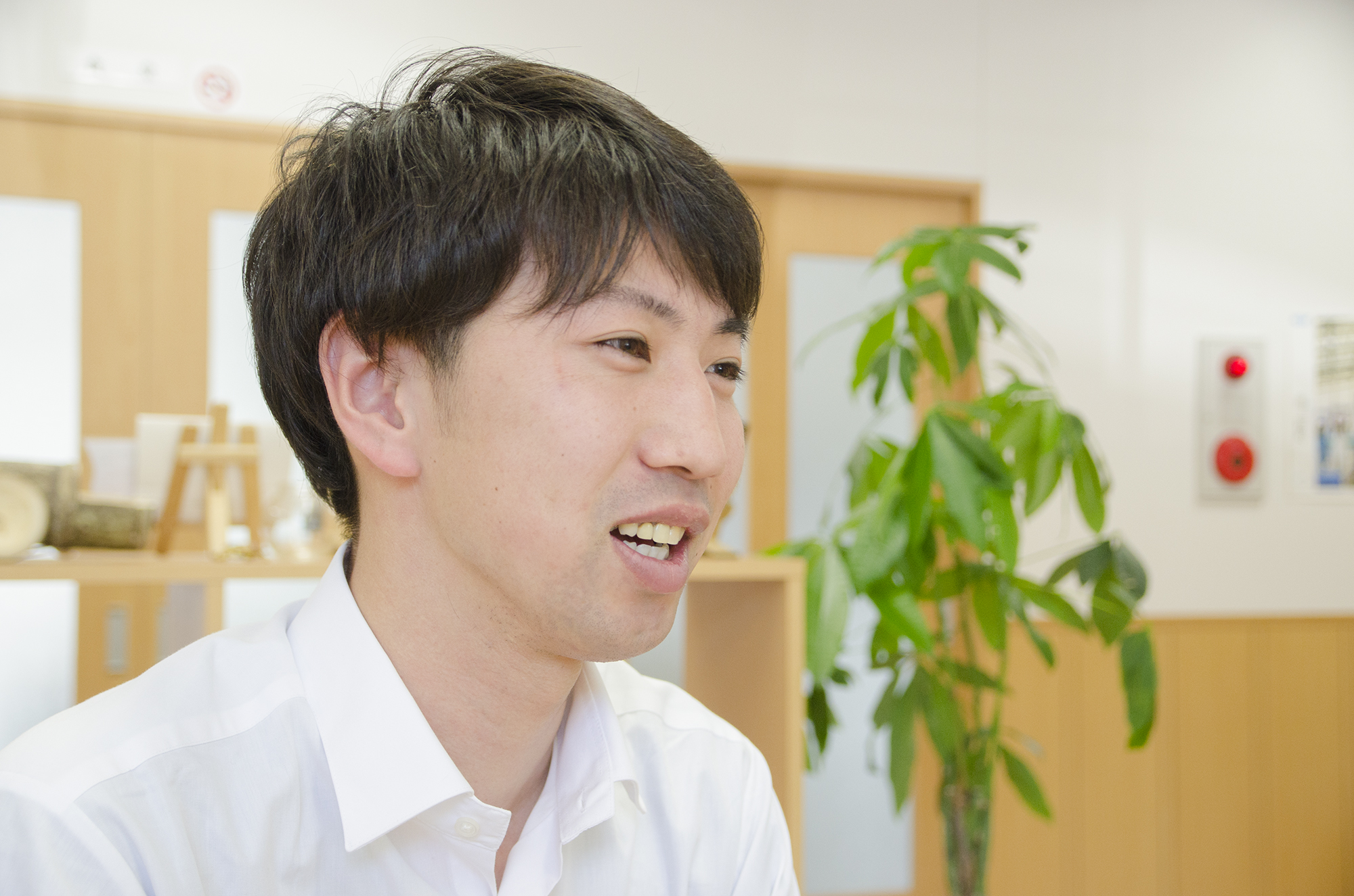 白いシャツを着た野田篤秀さんが屋内で話をしている横顔の写真