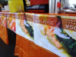 出店のチラシ、「海鮮クレープ」が店舗まえに何枚も掲示されている写真