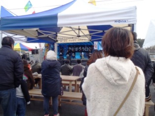 イベント会場で、ステージでの催しを観覧する人々の様子を写した写真