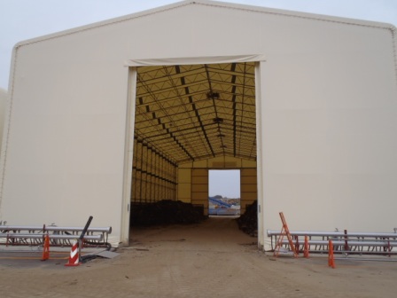 入口が大きく開いた白い大きなテントの内部に災害廃棄物が山積みにされている写真