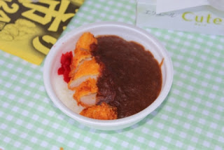 白いプラスチック製の皿に盛りつけられたタコカツにカレーがかけられたさんさんタコカレーの写真