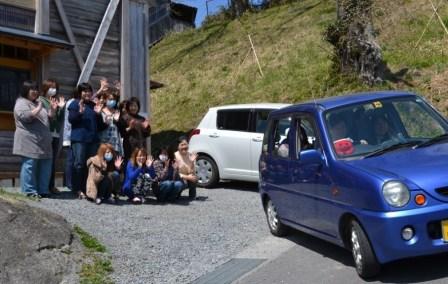 オクトパス君の乗った軽自動が出発し、みんなでお見送りをして手を振っている写真