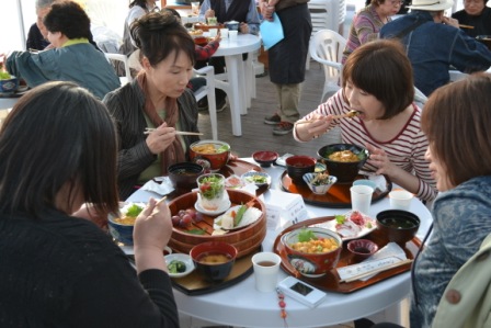 4人の女性が白い丸テーブルを囲み、食事を楽しんでいる様子の写真