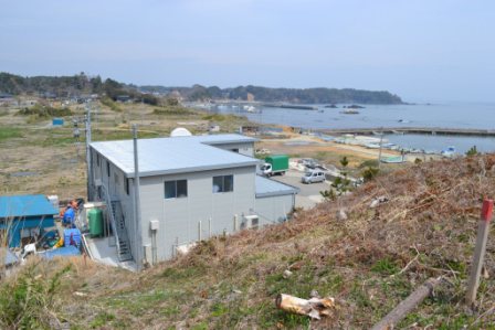山の下に見える工場とその先に見える海を写した写真