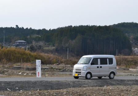 かさ上げされ高くなった舗装した道路を白いバンが走行している写真