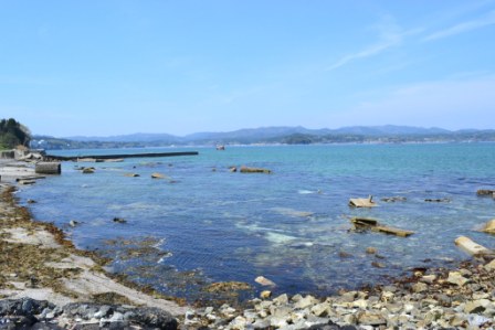岩がゴツゴツと転がりコンクリートの破片が散らばっている海岸の写真