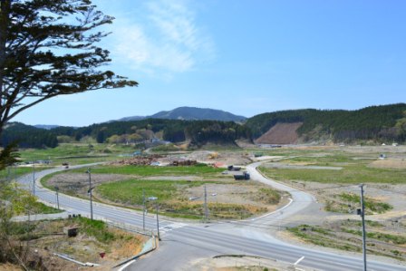 広い空き地が広がり中央を曲がりくねった道路が通り、空き地の周辺に道路が通っている写真