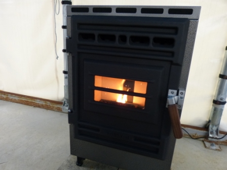 黒と灰色の直方体のペレットストーブの前面にある横長の長方形の耐熱ガラス窓からオレンジ色の炎が見えている写真