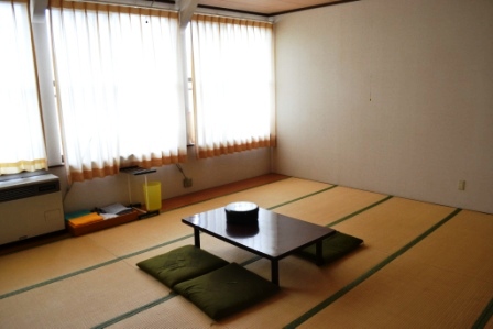 畳敷きの和室に座布団と座卓が置かれていて、落ち着いた雰囲気の室内を写した写真