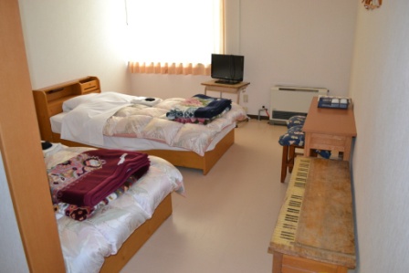 シングルベッドが2つ並び、テレビや机などの家具も備わった洋室の客室の写真