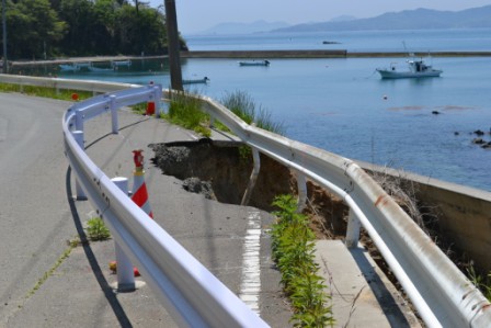 海沿いに伸びる道路の一部が崩れ、ガードレールが新しく設置された崩れた道路の箇所を大きく写した写真