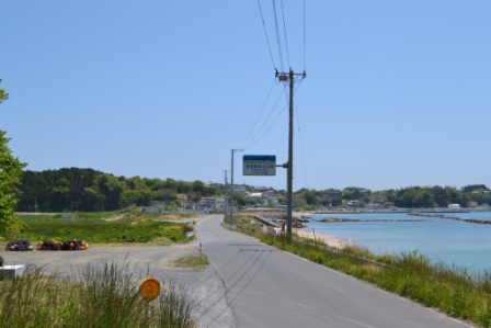 右側には海が広がり左側には山が広がっているまっすぐ伸びる道路を写した写真