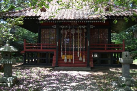 神社に7本の鐘が均等にぶら下がり左右には石灯籠が並び地面には花びらが散っている写真