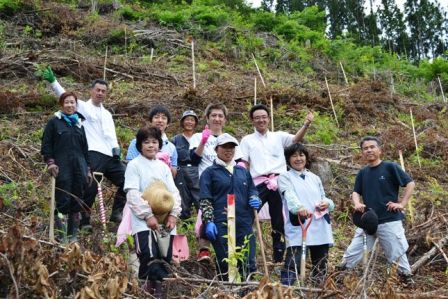 植樹作業の参加者の皆さんが山の斜面で、ポーズをとっている集合写真