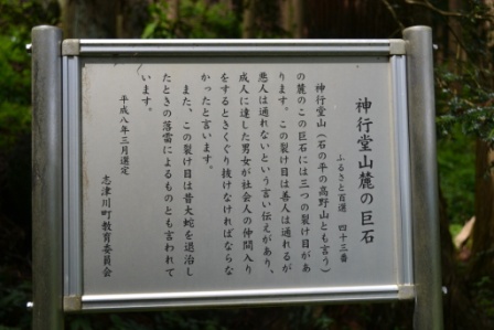 銀色でステンレス製の説明版に「神行堂山麓の巨石」に関する言い伝えの詳細が書かれた写真