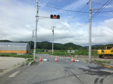 赤信号が点灯した交差点で、進入禁止のパイロンとバーで道路が封鎖されている写真