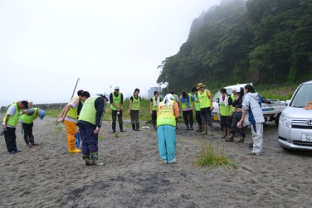 ボランティアの参加者の方々が清掃活動の最後に浜辺で円陣を組み一礼している解散前のあいさつの写真