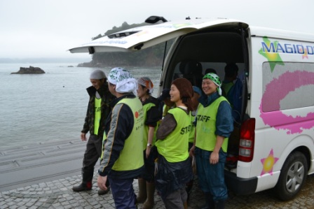海岸近くの車の前で笑顔で会話している後片付けのひとときの写真
