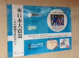 青い背景に「東日本大震災～あの瞬間を忘れない～」と書かれたポスターが壁に貼られ、震災の語り部活動の紹介や、展示会場の地図などが記載されている広報用の案内掲示物の写真