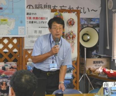 名札をつけた阿部博之さんがマイクをもって話をしている様子の写真