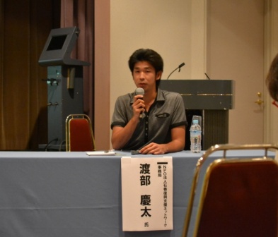 渡部慶太さんがマイクをもって話をしている様子の写真