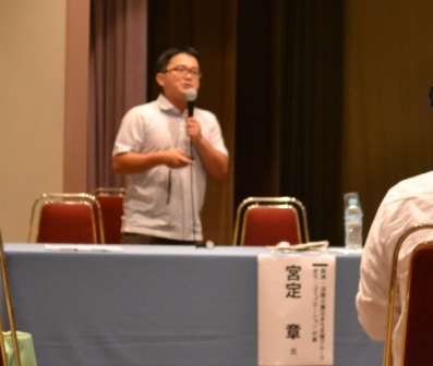 宮定章さんがマイクをもって話をしている様子の写真