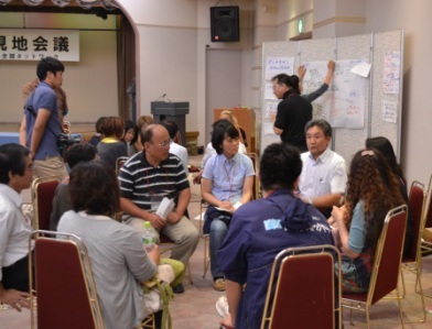 円形に椅子を並べて話し合いをしている10人ほどの参加者たちが、和やかかつ真剣に地域の課題や支援のあり方について語り合っているグループセッションの写真