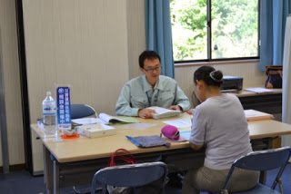 男性スタッフが書類を示しながら、向かいに座る女性に丁寧に説明している、相談窓口の様子の写真